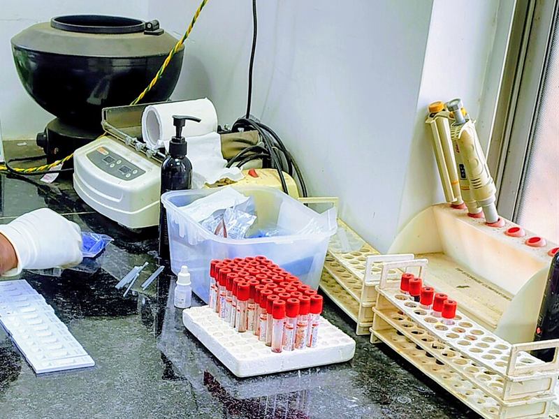 Blood sample tubes, racks and a centrifuge on a pathology lab bench