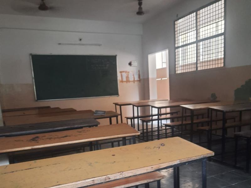 Indian classroom with a green blackboard and wooden benches