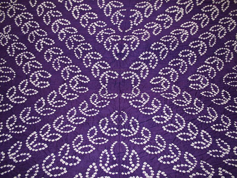 Purple bandhani fabric with white tie-dye dots in a floral pattern