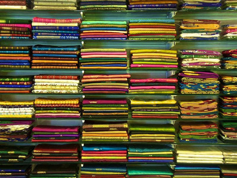 Shelves of folded silk sarees in many colours in a sari shop
