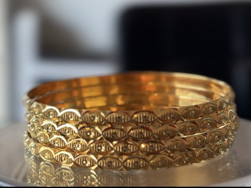 Four engraved 22-carat gold bangles on a display stand