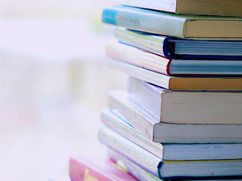 A tall stack of textbooks on a table
