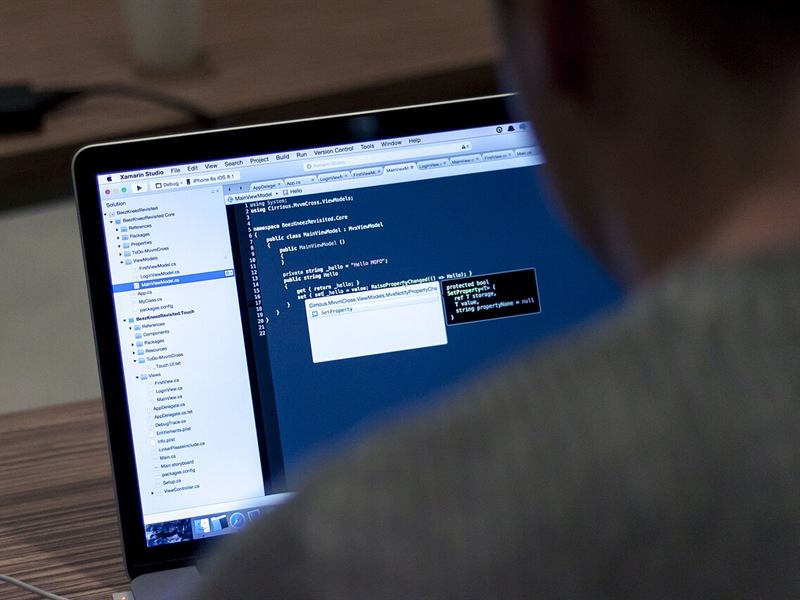 Code on a laptop screen seen over a developer’s shoulder